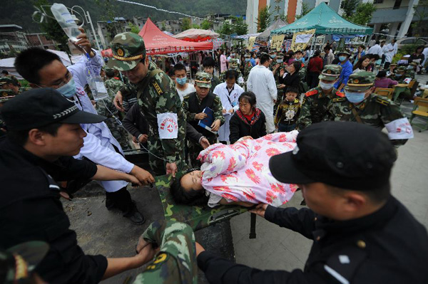 Rescuers transfer an injured person in Lingguan Town of Baoxing County in Ya'an City, southwest China's Sichuan Province, April 21, 2013. A 7.0-magnitude earthquake hit Lushan County of Sichuan Province on Saturday morning, leaving 26 people dead and 2,500 others injured, including 30 in critical condition, in neighboring Baoxing County, county chief Ma Jun said. [Xue Yubin/Xinhua]