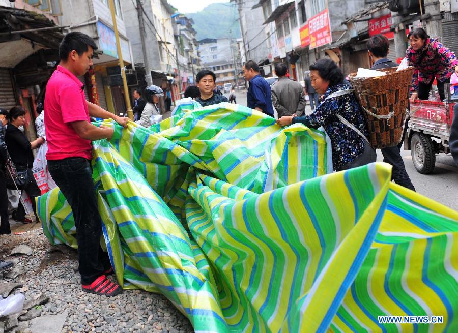 Locals buy water-proof cloth in Lushan County in Ya'an City, southwest China's Sichuan Province, April 21, 2013. Locals tried to get their lives back soon as the 7.0-magnitude earthquake hit Lushan County of Sichuan Province on Saturday morning, leaving 180 killed and 11,227 injured so far. [Xiao Yijiu/Xinhua]