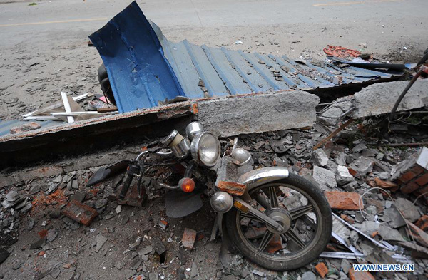 A motorbike is crushed by a fallen object in Lingguan Town of Baoxing County in Ya'an City, southwest China's Sichuan Province, April 21, 2013. A 7.0-magnitude earthquake hit Lushan County of Sichuan Province on Saturday morning, leaving 26 people dead and 2,500 others injured, including 30 in critical condition, in neighboring Baoxing County, county chief Ma Jun said. [Xue Yubin/Xinhua]