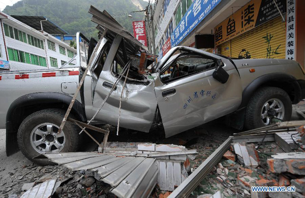 A vehicle is crushed by a fallen object in Lingguan Town of Baoxing County in Ya'an City, southwest China's Sichuan Province, April 21, 2013. A 7.0-magnitude earthquake hit Lushan County of Sichuan Province on Saturday morning, leaving 26 people dead and 2,500 others injured, including 30 in critical condition, in neighboring Baoxing County, county chief Ma Jun said. [Xue Yubin/Xinhua]