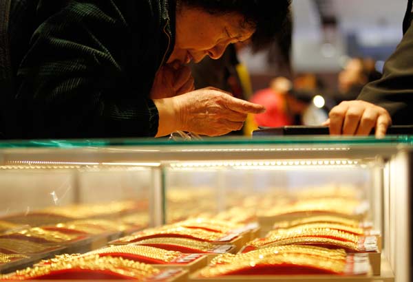 A senior citizen examining gold necklaces at a department store in Nanjing, capital of East China's Jiangsu province. Many senior citizens believe that it is an opportune time to buy the yellow metal as prices have plummeted to a historical low in over 30 years. [China Daily]