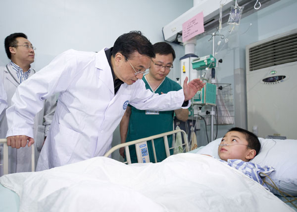 Premier Li Keqiang consoles a young earthquake victim in a hospital in Chengdu on Sunday. [Photo/Xinhua]    