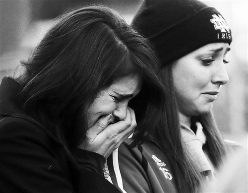 美国居民悼念枪击事件死难者：2012年12月15日，在美国康涅狄格州纽敦市，两名女子在悼念该州桑迪胡克小学枪击案遇难者的活动上痛哭。[新华社]