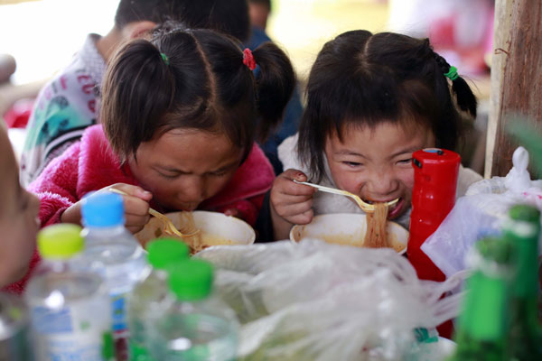Young survivors get a warm meal at a rescue center in Longmen township, Lushan, on Sunday. [Photo/China Daily] 