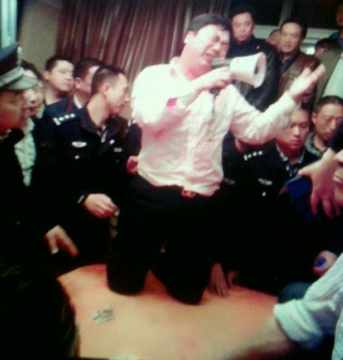 Zhang Aihua, Party secretary of the industrial zone, knelt on the table and kowtowed to the angry crowd.