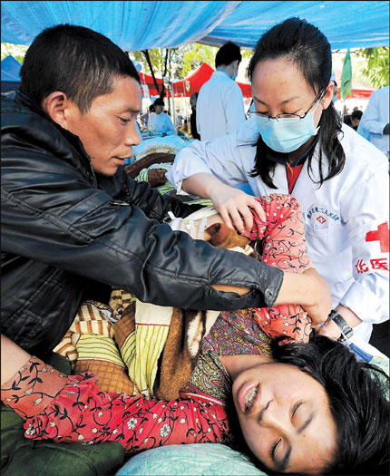 Medical staff from Peking University No. 3 Hospital treat a woman injured in the 7.0-magnitude earthquake in Sichuan Province at the Ya'an No. 2 People's Hospital yesterday.