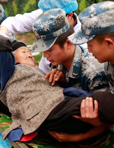 Rescuers carry 94-year-old Chen Guizhen to a safe area in Lushan county's Qinglongchang village, Sichuan province, on Monday. The village was one of the areas hit hardest by the magnitude-7 earthquake on Saturday. [Photo/ China Daily] 