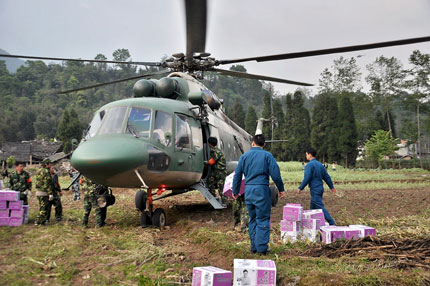 Soldiers move cartons of instant noodles in Sichuan Province's Lushan County. Helicopters airlifted relief supplies to Lushan and Baoxing counties in the earthquake-hit region yesterday afternoon.