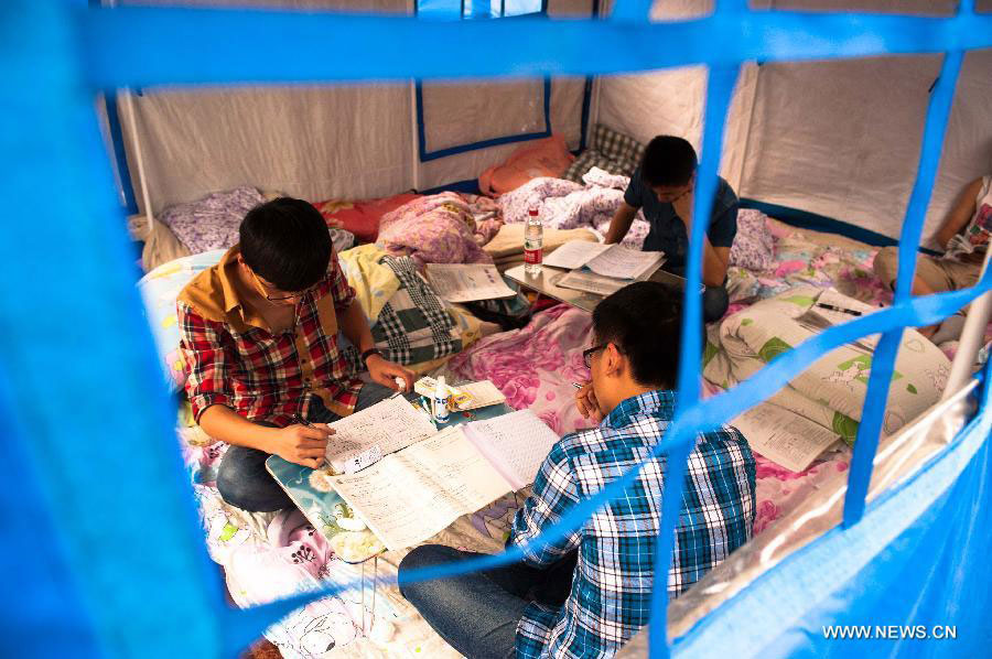 High school students study to prepare the college entrance exam this summer outside tents at a temporary settlement at the Tianquan Middle School in quake-hit Tianquan County, Ya'an City, southwest China's Sichuan Province, April 22, 2013. [Photo/Xinhua] 