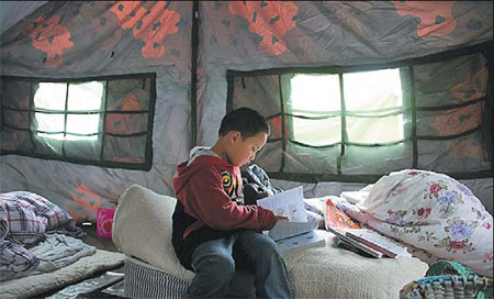 Yang Xuxue, 5, reading in the tent that now serves as his home.