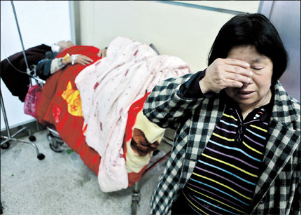 The grandmother of Zhang Chao, the six-year-old who died in the traffic accident, cries at Xinhua Hospital. Behind her is her husband, Zhang Zhizhong, who had severe but not lifethreatening injuries.