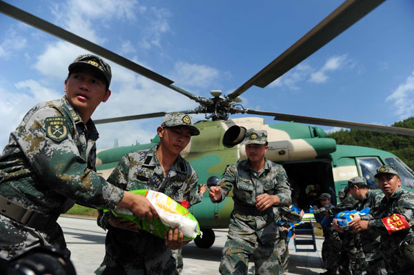 Soldiers from the Chengdu Military Command Area load a bag of rice onto a helicopter heading to quake-hit areas in Lushan, Sichuan province, on Wednesday. [Photo/China Daily]
