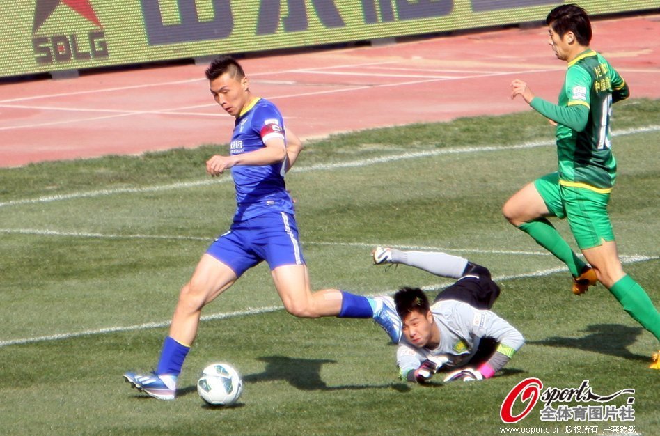 Yu Dabao of Dalian Aerbin dribbles past Beijing Guoan's goalkeeper Hou Sen to open the scoring in a Chinese Super League match in Dalian on April 27, 2013. 