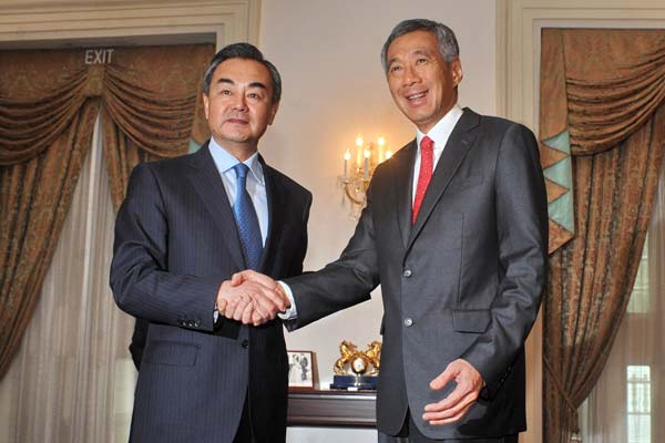 Foreign Minister Wang Yi (left) shakes hands with Singaporean Prime Minister Lee Hsien Loong during a meeting at the Istana presidential palace in Singapore on Friday. Wang was on a two-day visit in Singapore, his first official visit as foreign minister. [MOHD FYROL / AFP]