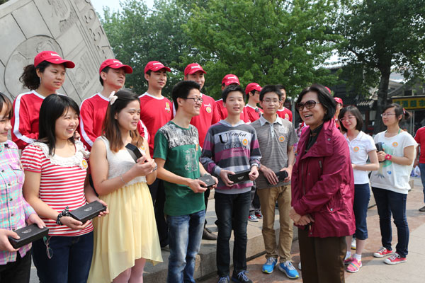 Secretary-general Wu Peifu who is in charge of the special assistance fund set up by the China Children and Teenagers' Fund and Amway (China) Corporation talks to college students from central China's Hubei Province who have received financial assistance from the program during their visit to May Fourth Avenue in Beijing on Saturday, May 4, 2013. [Photo/CRIENGLISH.com]
