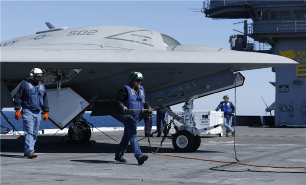 Workers prepare an X-47B pilot-less drone combat aircraft to be launched for the first time off an aircraft carrier, the USS George H. W. Bush, in the Atlantic Ocean off the coast of Virginia, May 14, 2013.