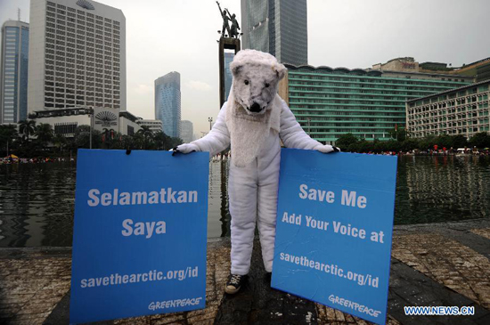 An environmentalist in polar bear costume holds placards during an Arctic-saving campaign in Jakarta, Indonesia, May 12, 2013. 