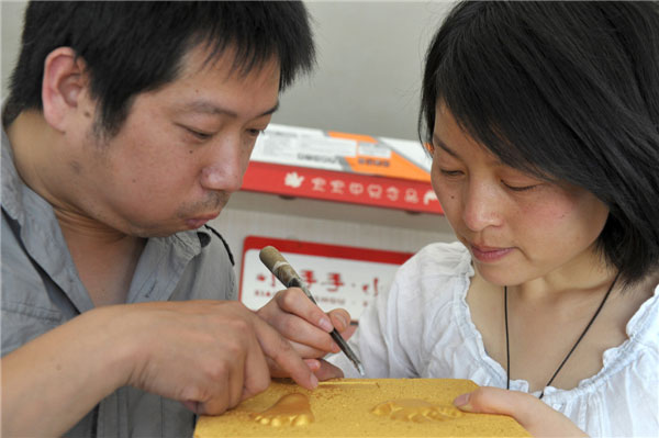 The couple make hand and footprint products at their shop in Hefei, capital of East China's Anhui province on May 14, 2013. [Photo/Xinhua]