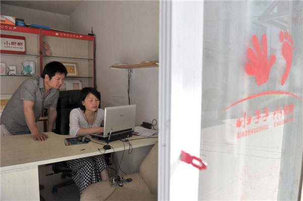 Zhan Yi, left, and Wu Tengli check online orders for hand and footprint products at their shop in Hefei, capital of East China's Anhui province on May 14, 2013. [Photo/Xinhua]