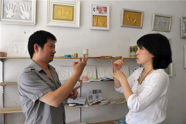 Zhan Yi, left, and Wu Tengli communicate in sign language at their shop in Hefei, capital of East China's Anhui province on May 14, 2013. [Photo: Xinhua]