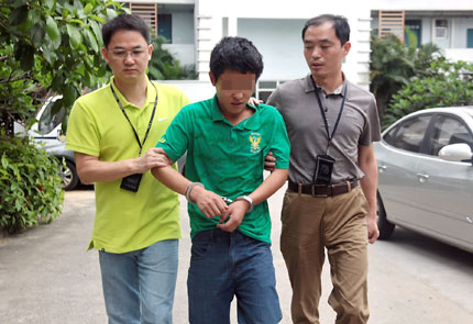  The suspected hoax caller (center) is escorted by plainclothes officers after his detention.