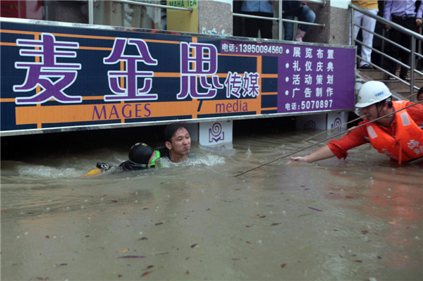 Rescuers try to help a man trapped by flooding in Xiamen city, Fujian province on May 16, 2013. The man was trapped in the water for eight hours before being rescued. [Photo by Mo Feng/Asianewsphoto]