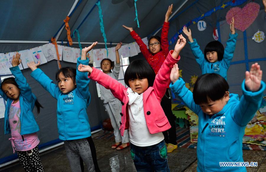 Children take a dance class in a temporarily-erected tent in Lushan County, southwest China's Sichuan Province, May 17, 2013. 