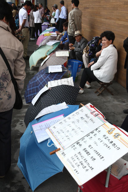 Parents pin their children's details to umbrellas, in the hope of finding a Mr or Ms Right for their offspring at Shanghai's largest matchmaking party yesterday. [Zhang Suoqing/Shanghai Daily]