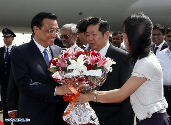 Chinese Premier Li Keqiang (L, front) receives flowers upon his arrival at an airport in New Delhi, India, kicking off an official visit to the country, on May 19, 2013. [Ju Peng/Xinhua]