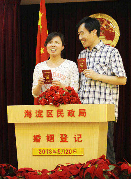 Newlyweds pose with their marriage license at the marriage registration office of civil affairs bureau of Haidian district in Beijing on Monday. [Photo / China Daily]