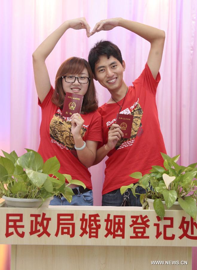 A bride and a bridegroom pose for photos after registering as a married couple in the registry of marriages in Sanya City, south China's Hainan Province, May 20, 2013. As the pronunciation of the date number '520' sounds like 'I love you' in Chinese, many people chose to register as couples on Monday. [Photo/Xinhua]