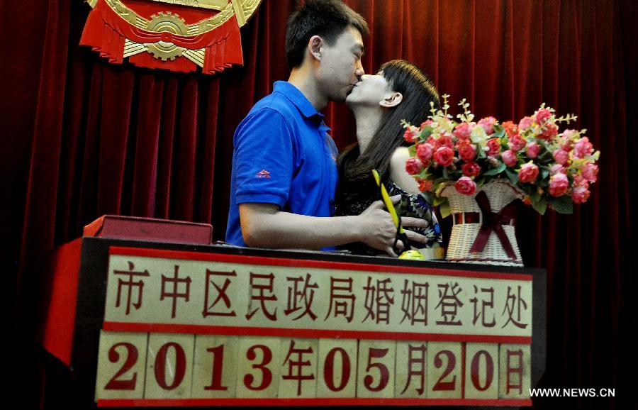 A bride and a bridegroom kiss after registering as a married couple at a marriage registry in Jinan City, east China's Shandong Province, May 20, 2013. As the pronunciation of the date number '520' sounds similiar to 'I love you' in Chinese, many people chose to register as couples on Monday. [Photo / Xinhua]