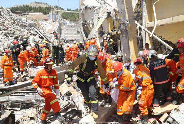 Rescuers pull a person out of the debris of a collapsed workshop after a massive blast ripped through a factory on Monday in Zhangqiu, Shandong province. The explosion killed 13 people. [Photo / China Daily]