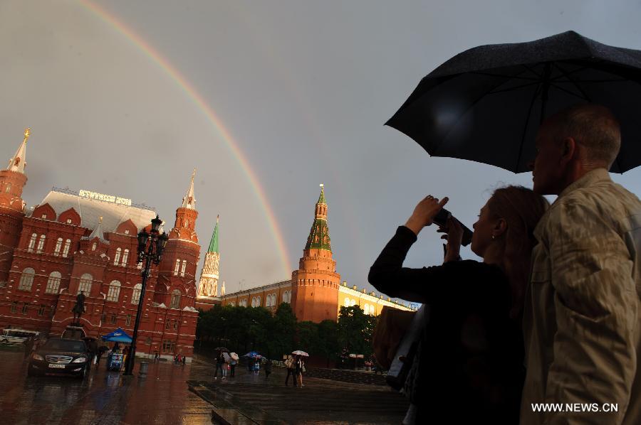 People take photos of a rainbow arching above Moscow's Red Square after a heavy rain on May 22, 2013. 