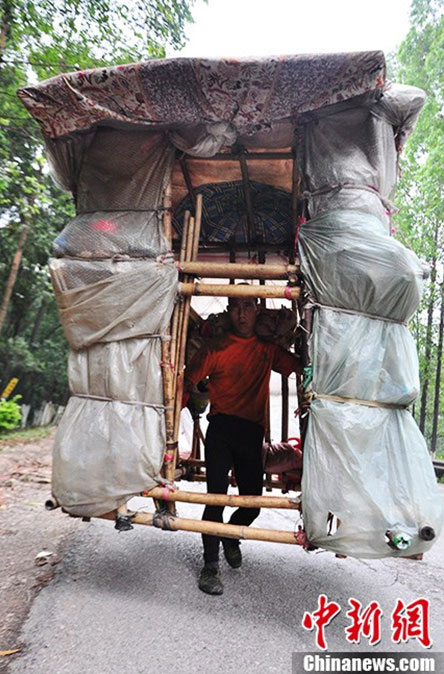 Liu Lingchao walks on a section of National Highway 209 in Liuzhou City with his simple and crude house on his shoulders on Tuesday, May 21, 2013. [Photo/chinanews.cn]