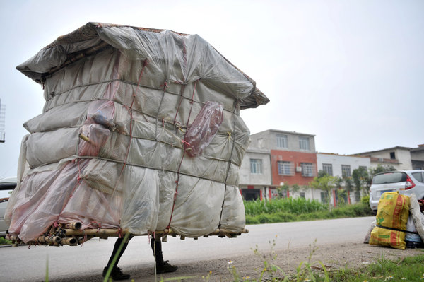 Liu Lingchao walks home carrying his self-built house in Liucheng county, May 21, 2013. [Photo/CFP]