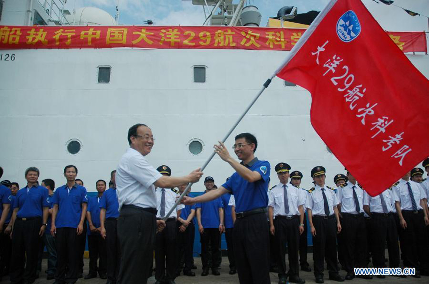 Wang Fei (L), director of China Ocean Mineral Resources Research and Development Association, confers a flag to a team member beside Haiyang-6, a Chinese research vessel, at a dock in Guangzhou, capital of south China&apos;s Guangdong Province, May 28, 2013. An expedition team of 96 members aboard Haiyang-6 set out for the Pacific Ocean Tuesday to carry out a five-month survey on undersea mineral resources. 