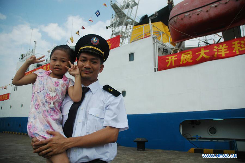 A member of an expedition team poses for a photo with his daughter beside Haiyang-6, a Chinese research vessel, at a dock in Guangzhou, capital of south China&apos;s Guangdong Province, May 28, 2013. An expedition team of 96 members aboard Haiyang-6 set out for the Pacific Ocean Tuesday to carry out a five-month survey on undersea mineral resources. 