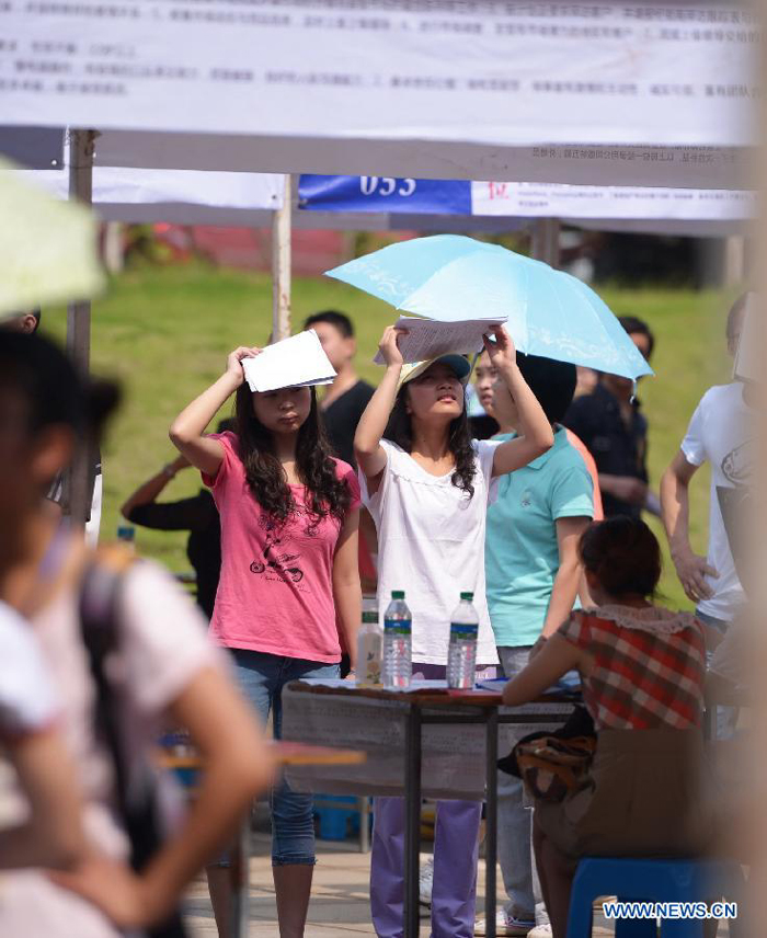 Applicants shelter sunshine with books when participating in a job fair in a college of Nanchang in Nanchang City, capital of east China&apos;s Jiangxi Province, May 23, 2013. Nanchang saw its highest temperature reaching 34 degrees celcius on Thursday, about 10 degrees higher than the same period in 2012.