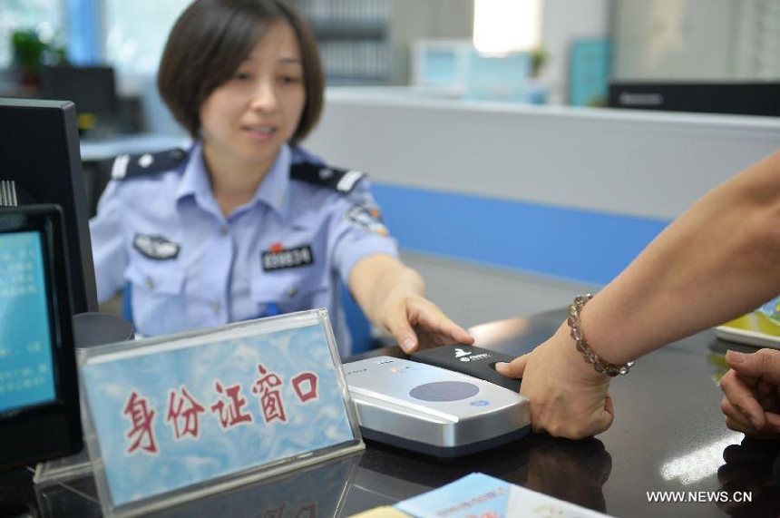 A policewoman guides a citizen in registering the fingerprint information for ID card recognition at the Wanshoulu Police Station in Beijing, capital of China, June 1, 2013. Beijing started the fingerprint information collection for its citizens&apos; ID card recognition on Saturday.