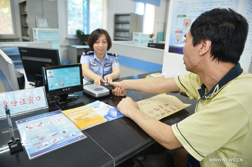 A policewoman guides a citizen in registering the fingerprint information for ID card recognition at the Wanshoulu Police Station in Beijing, capital of China, June 1, 2013. Beijing started the fingerprint information collection for its citizens&apos; ID card recognition on Saturday.