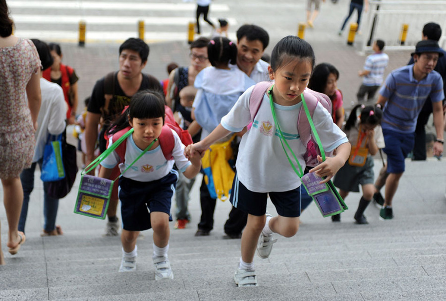 两名跨境儿童结伴爬上出境大楼楼梯，准备过关去香港上学。跨境学童在生活方面遇到的最大问题是交通，平均来香港的单程交通时间都要一个小时。香港上水惠州公立学校11岁的麦同学告诉记者，自己每天必须6点起床，才能保证7点到达罗湖口岸，8点准时到校上课。[新华社 赵宇思 摄]