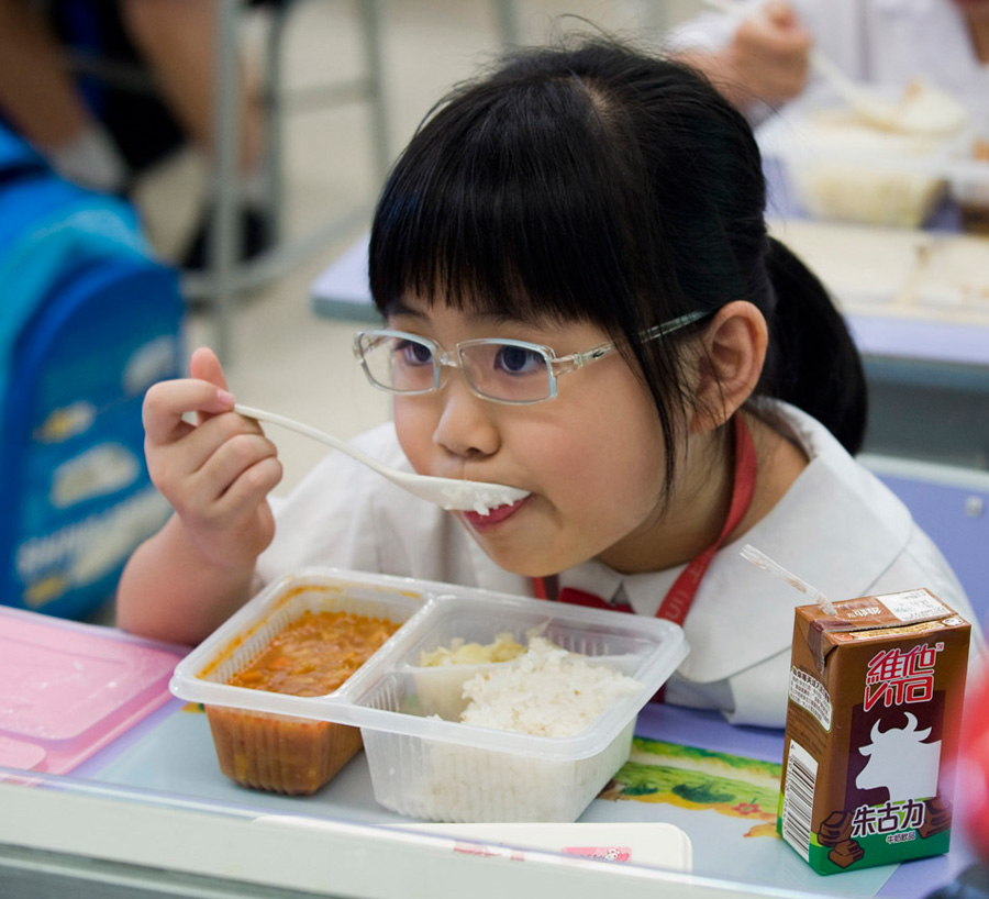 一名一年级小学生在吃午饭。一些家长表示，之所以辛苦送孩子去香港上学，一是因为小孩的香港身份在深圳只能就读价格高昂的国际学校或民办学校，而香港政府推出了幼儿园“学券制”等一系列学费补贴政策。二是因为深港两地的教学内容不同。[新华社 赵宇思 摄]