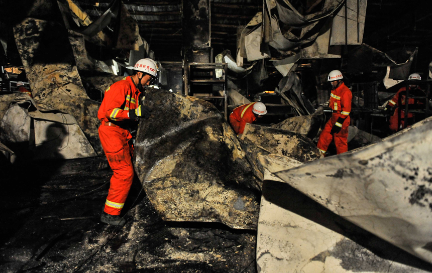 Fire fighters are pictured next to a burnt poultry slaughterhouse owned by the Jilin Baoyuanfeng Poultry Company in Mishazi Township of Dehui City in northeast China&apos;s Jilin Province, June 3, 2013. The death toll from the fire has risen to 119 as of 8 p.m. on Monday. Search and rescue work is under way. [Photo/Xinhua]