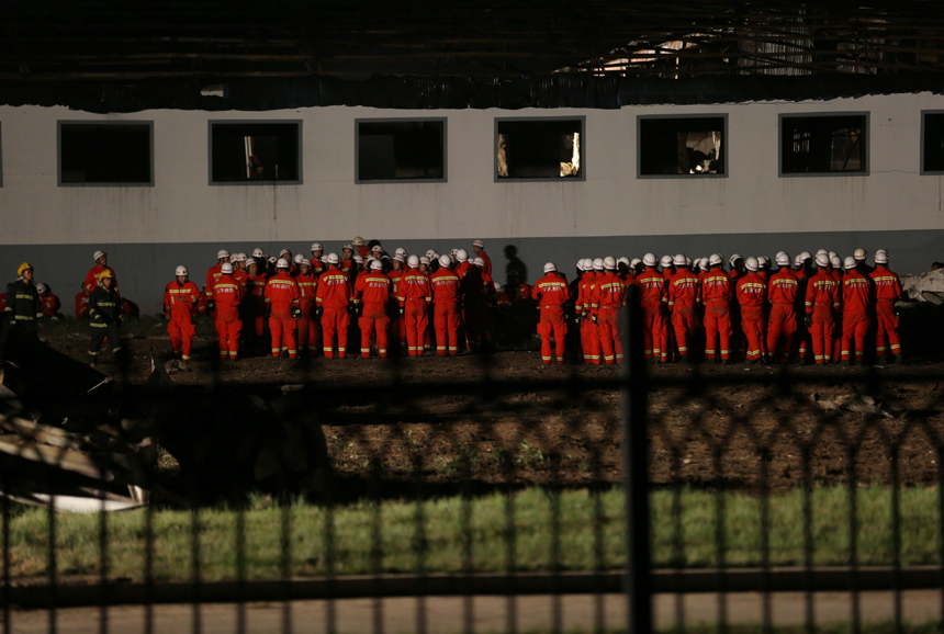 Fire fighters are pictured next to a burnt poultry slaughterhouse owned by the Jilin Baoyuanfeng Poultry Company in Mishazi Township of Dehui City in northeast China&apos;s Jilin Province, June 3, 2013. The death toll from the fire has risen to 119 as of 8 p.m. on Monday. Search and rescue work is under way. [Photo/Xinhua]