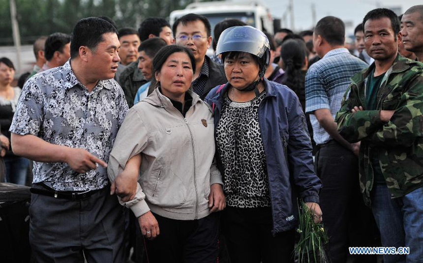 People wait for news of their relatives trapped in a burnt poultry slaughterhouse owned by the Jilin Baoyuanfeng Poultry Company in Mishazi Township of Dehui City in northeast China&apos;s Jilin Province, June 6, 2013. The death toll from the fire has risen to 119 as of 8 p.m. on Monday. Search and rescue work is under way. 