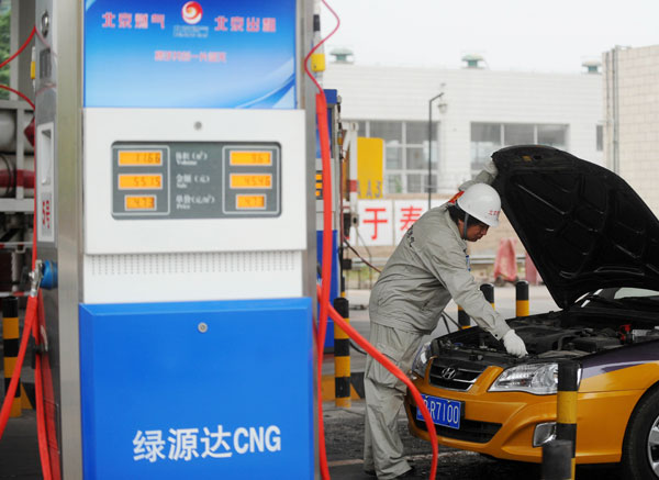 A gas station worker fills a natural gas-fueled taxi in Beijing on Tuesday. [Xinhua]