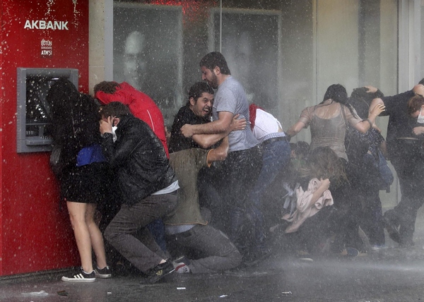 Anti-government protesters try to protect themselves from a water cannon as riot police disperse them during a protest in Ankara June 5, 2013. Turkish demonstrators demanded the sacking of police chiefs on Wednesday over a fierce crackdown on days of unprecedented protest against what they see as Prime Minister Tayyip Erdogan's authoritarian rule.[Agencies via China Daily] 