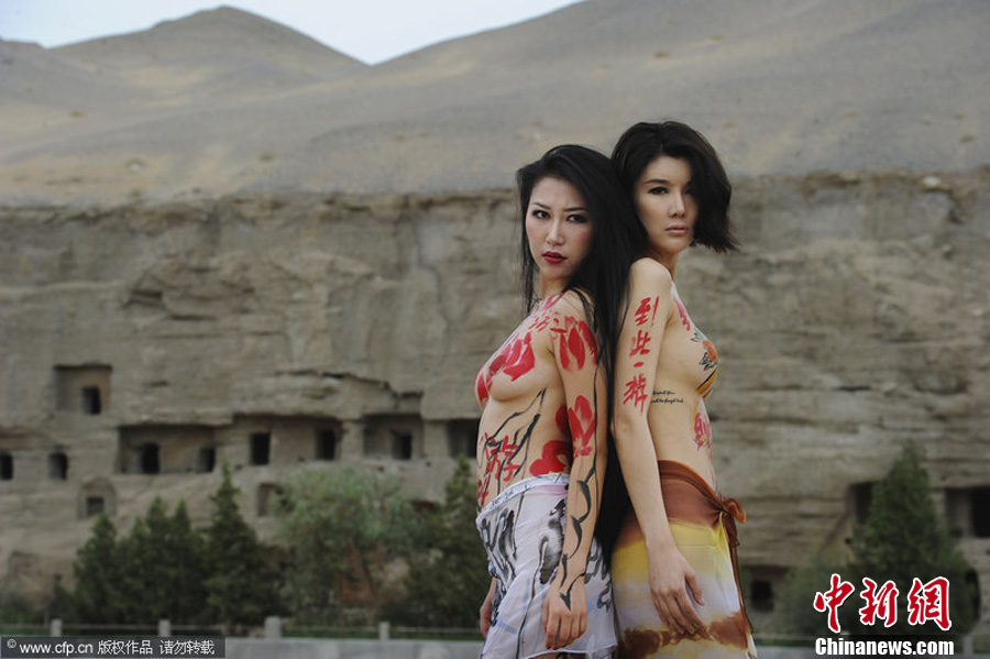 Two female body-paint models pose on the ground outside the Mogao Grottoes in Jiuquan City, in northwestern China’s Gansu Province. The models are volunteers for a campaign to protect the Mogao Grottoes. The campaign, which was initiated by the non-governmental organization Idea Beautify China, also aims to raise awareness about preserving historic and cultural heritage elsewhere.