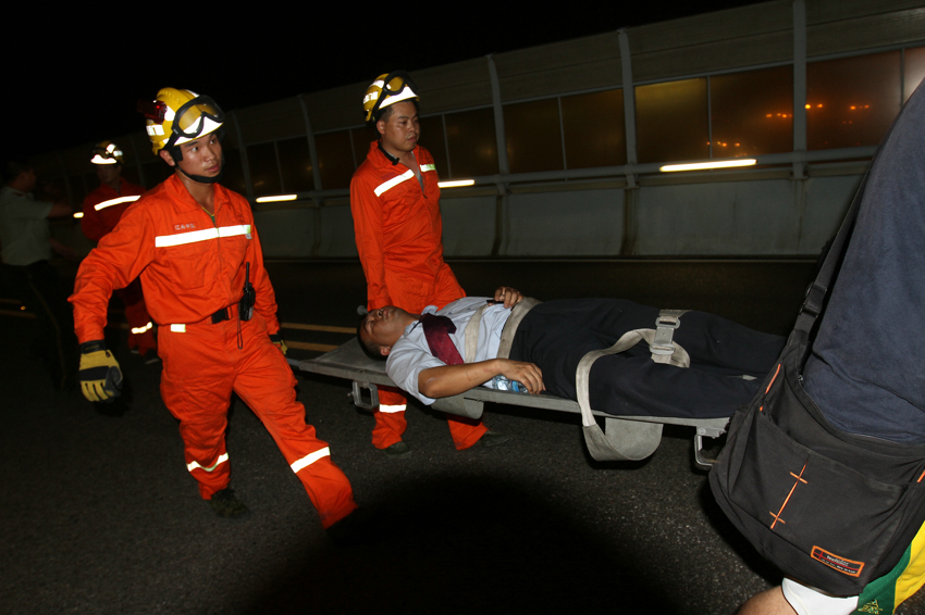 Photo taken on June 7, 2013 shows rescuers carry an injured man from the bus on fire on an elevated track in Xiamen, southeast China&apos;s Fujian Province. At least 48 people died and more than 30 others were injured after the bus in the city&apos;s BRT (bus rapid transit) service burst into flames at about 6:30 p.m. on Friday. [Photo/Xinhua]